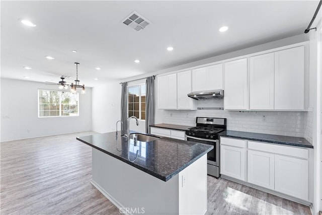 kitchen with visible vents, gas range, light wood-style flooring, under cabinet range hood, and a sink