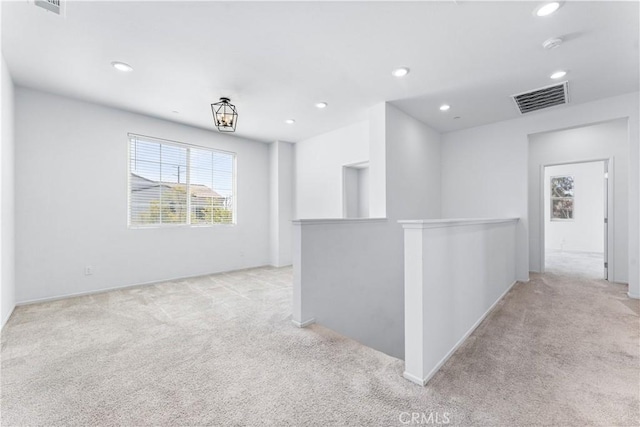 interior space featuring light carpet, recessed lighting, visible vents, and an upstairs landing