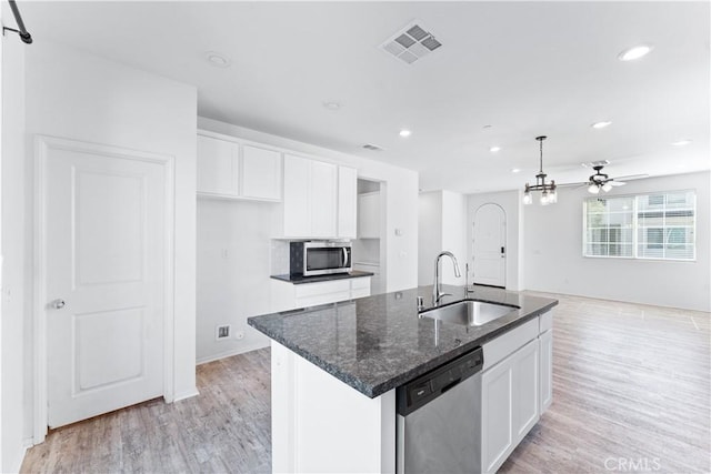 kitchen with stainless steel appliances, a sink, visible vents, and white cabinetry