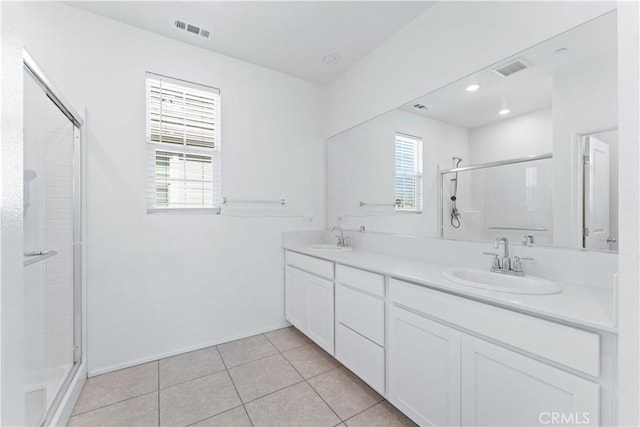 bathroom with a stall shower, tile patterned flooring, visible vents, and a sink