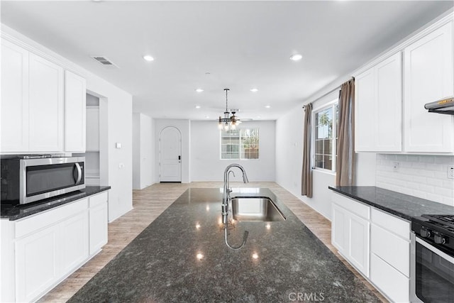 kitchen with stainless steel appliances, visible vents, backsplash, a sink, and light wood-type flooring