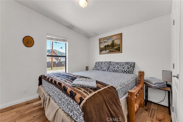 bedroom with baseboards, vaulted ceiling, and wood finished floors