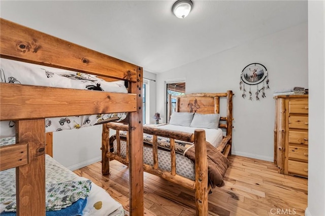 bedroom with lofted ceiling, baseboards, and wood finished floors