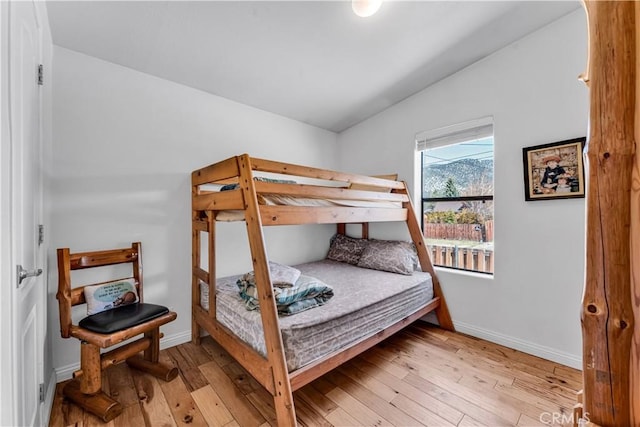 bedroom featuring lofted ceiling, light wood-style flooring, and baseboards