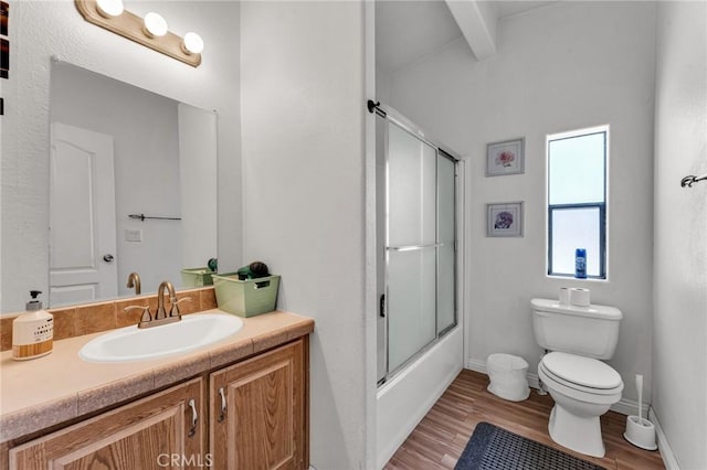 full bathroom featuring beam ceiling, shower / bath combination with glass door, toilet, vanity, and wood finished floors