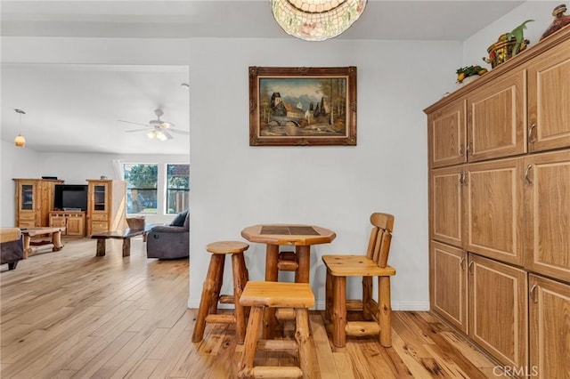 dining area with baseboards, light wood-style flooring, and a ceiling fan