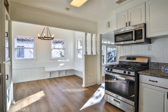 3255 N Arrowhead Ave, San Bernardino, CA 92405 - kitchen with dark stone countertops, wood finished floors, an inviting chandelier, stainless steel appliances, and white cabinets