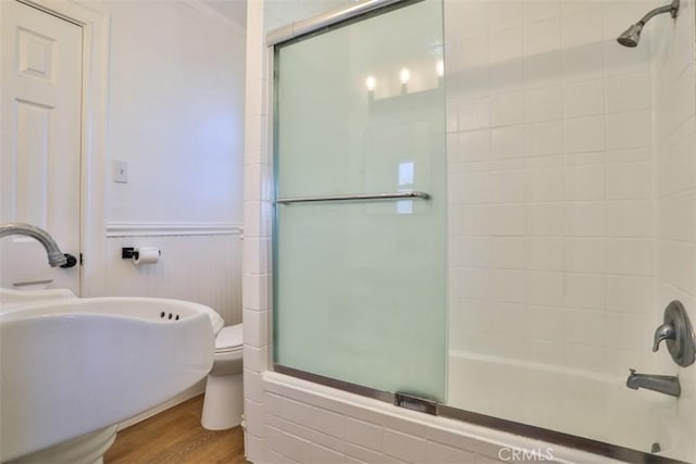 full bath featuring bath / shower combo with glass door, a sink, toilet, and wood finished floors