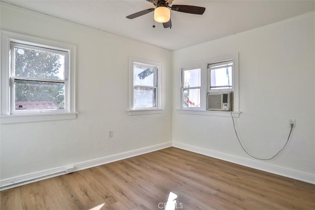 spare room featuring a ceiling fan, cooling unit, baseboards, and wood finished floors