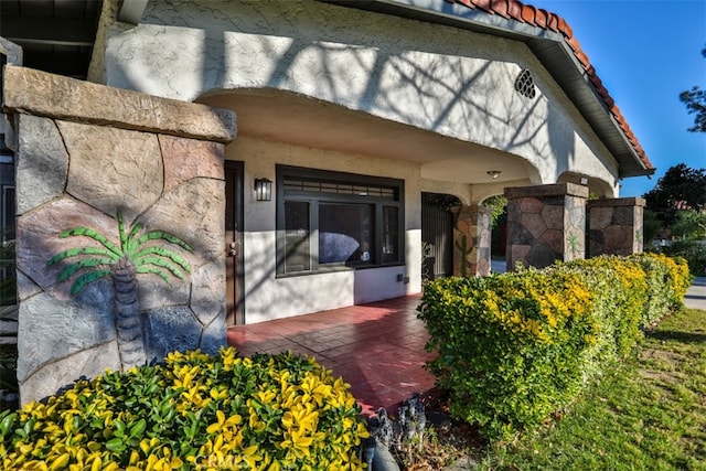 entrance to property featuring a tile roof and stucco siding