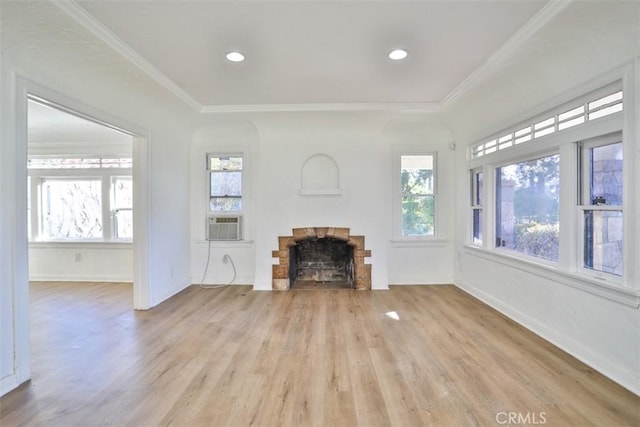 unfurnished living room with cooling unit, a brick fireplace, crown molding, and light wood-style flooring