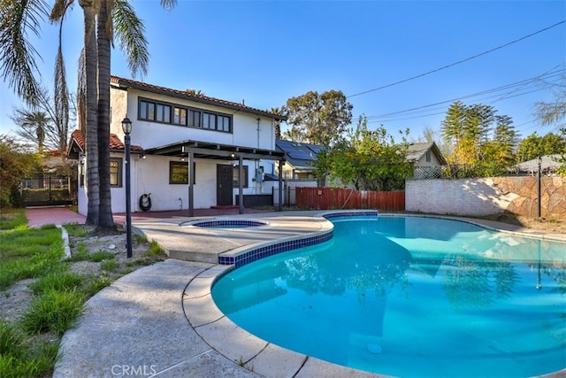 rear view of house featuring a fenced in pool, a patio, stucco siding, an in ground hot tub, and a fenced backyard