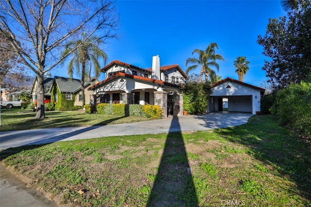 view of front of house featuring a tile roof, a chimney, concrete driveway, a front yard, and a garage