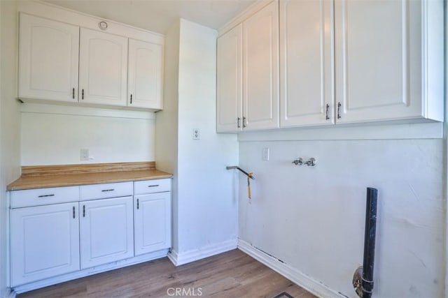 clothes washing area with hookup for a washing machine, baseboards, cabinet space, and wood finished floors