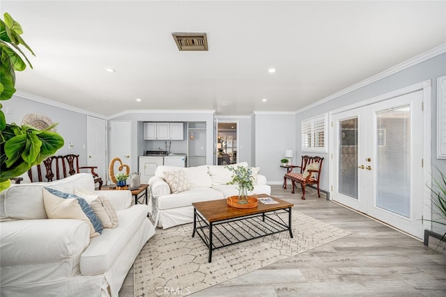 living room with washing machine and dryer, visible vents, crown molding, and french doors