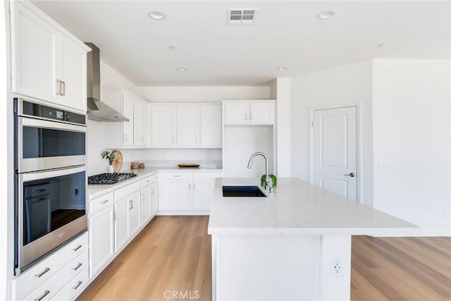 12945 Big Valley Ct, Riverside, CA 92503 - kitchen with light wood-style floors, visible vents, wall chimney exhaust hood, appliances with stainless steel finishes, and a sink