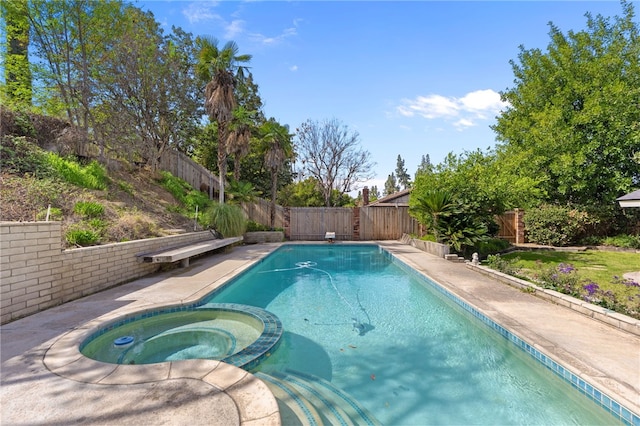 view of pool with a fenced backyard and a pool with connected hot tub