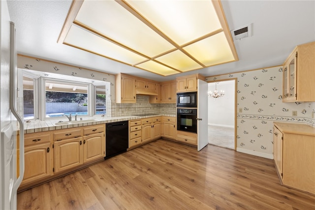 kitchen featuring wallpapered walls, visible vents, light wood-style flooring, black appliances, and a sink