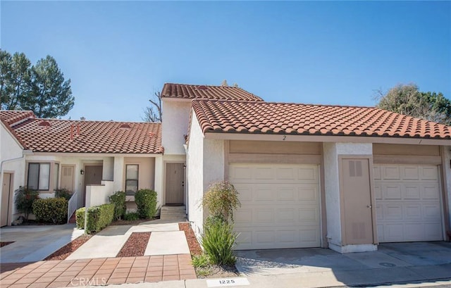 view of front of house featuring a garage, concrete driveway, a tile roof, and stucco siding