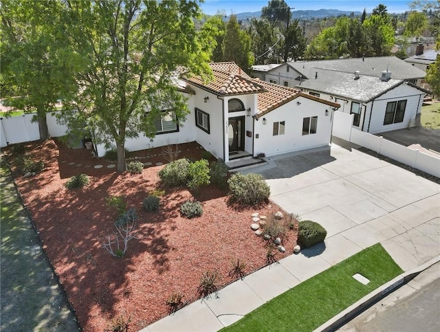 mediterranean / spanish house with a tile roof, fence, and stucco siding