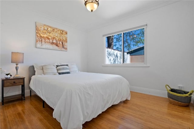 bedroom featuring crown molding, baseboards, and wood finished floors