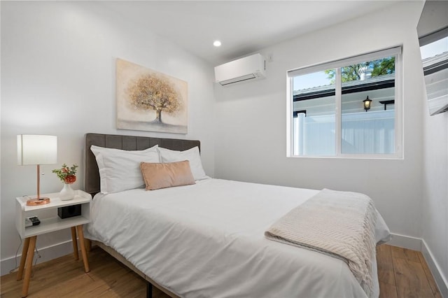 bedroom featuring recessed lighting, baseboards, wood finished floors, and a wall mounted AC