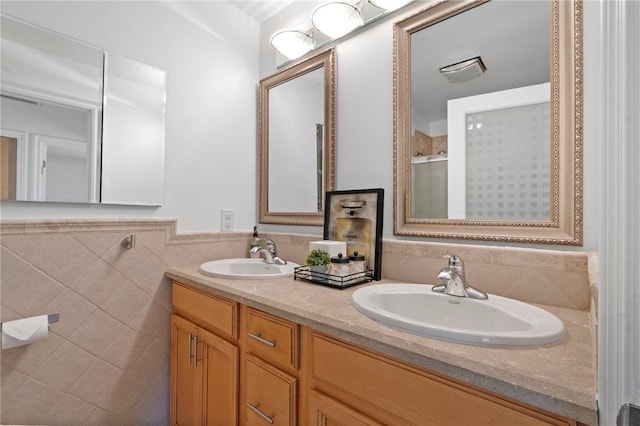 full bathroom featuring double vanity, a shower stall, a sink, and wainscoting