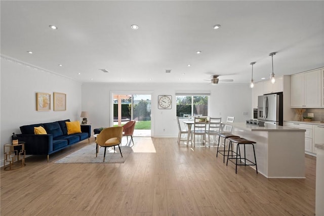 living room featuring ornamental molding, light wood-type flooring, a ceiling fan, and recessed lighting