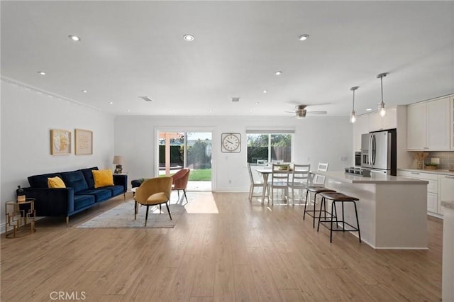 living area featuring light wood-style flooring, a ceiling fan, crown molding, and recessed lighting