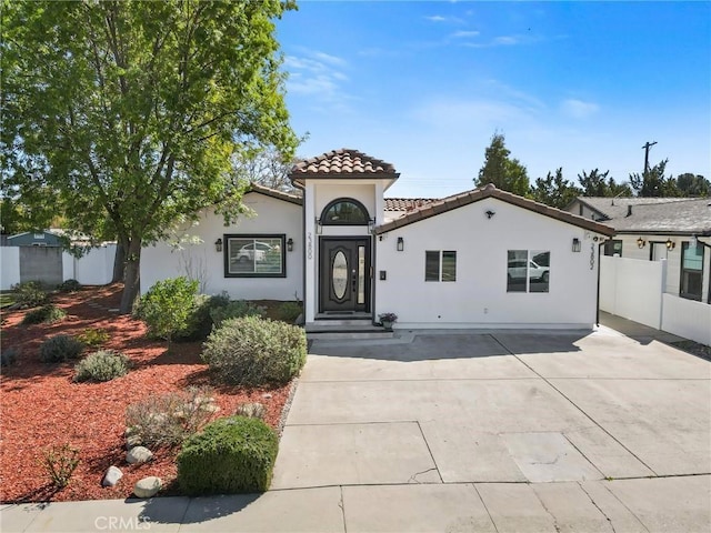 view of front of house with fence, a tiled roof, and stucco siding