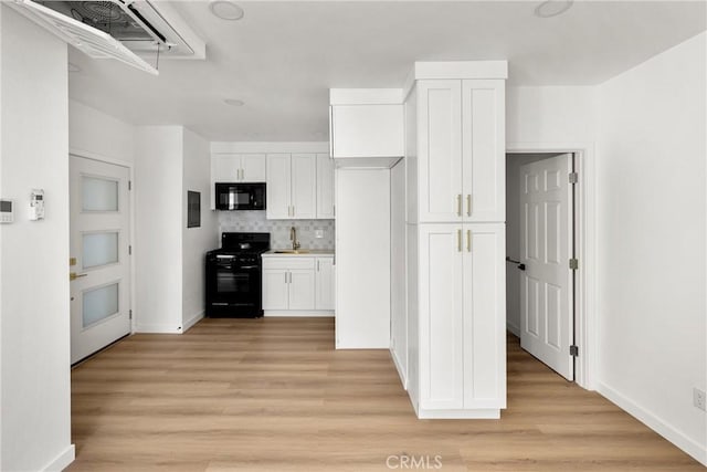 kitchen featuring decorative backsplash, light wood-style floors, white cabinets, black appliances, and a sink