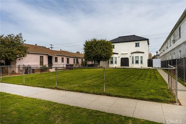 exterior space with a front yard, fence, and stucco siding