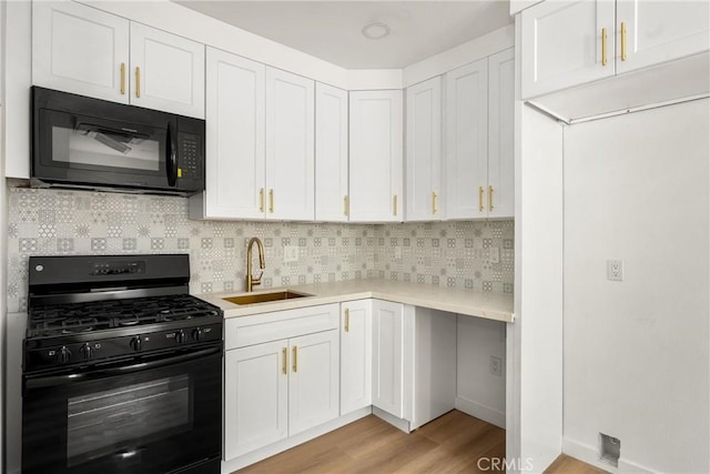 kitchen featuring black appliances, tasteful backsplash, a sink, and light countertops