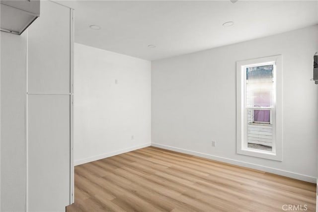 unfurnished room with baseboards and light wood finished floors