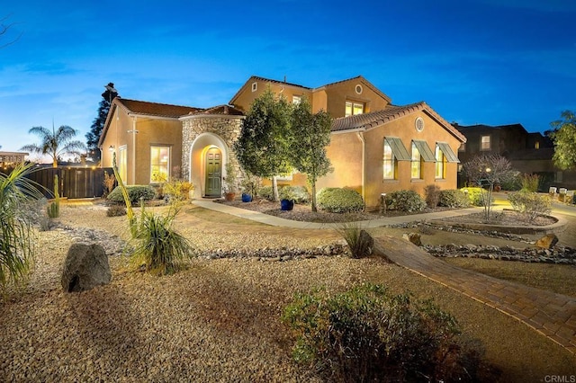 view of front of home featuring a chimney, stucco siding, fence, stone siding, and a tiled roof