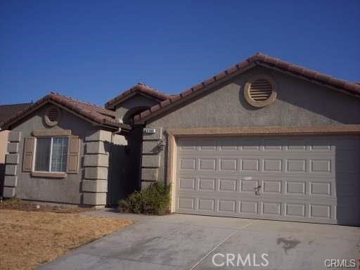 view of front facade featuring a tiled roof, an attached garage, and driveway