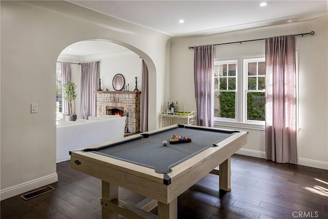 recreation room with dark wood-style floors, visible vents, a fireplace, and baseboards