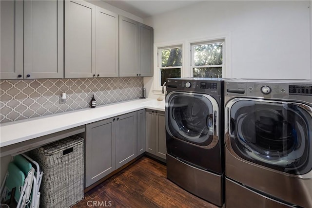 clothes washing area with dark wood-style flooring, cabinet space, a sink, and washing machine and clothes dryer