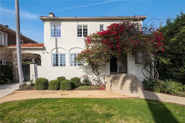 traditional home with a front yard, a chimney, and stucco siding