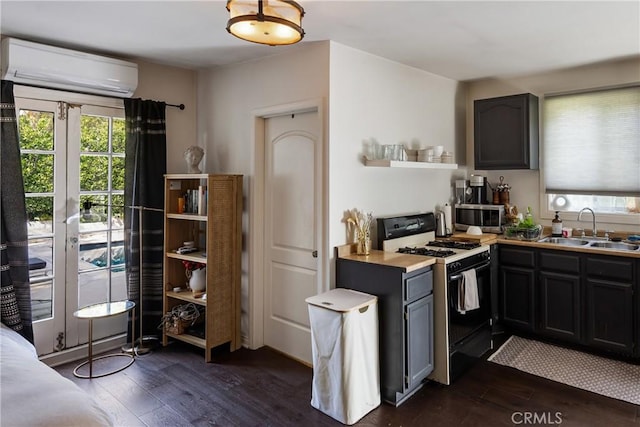 kitchen with gas range, dark wood-style floors, a sink, and an AC wall unit