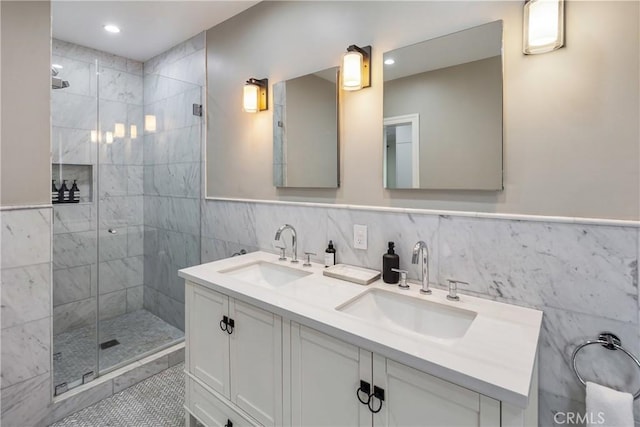 full bathroom with double vanity, a shower stall, tile walls, and a sink