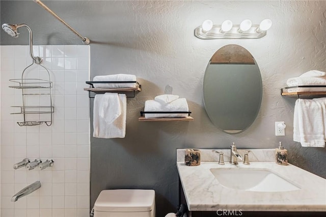 bathroom with washtub / shower combination, a textured wall, vanity, and toilet