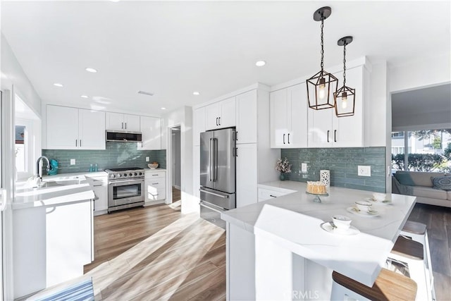 kitchen with a peninsula, high end appliances, a sink, and light countertops