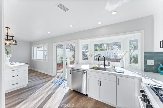 kitchen with visible vents, decorative backsplash, range, stainless steel dishwasher, and a sink