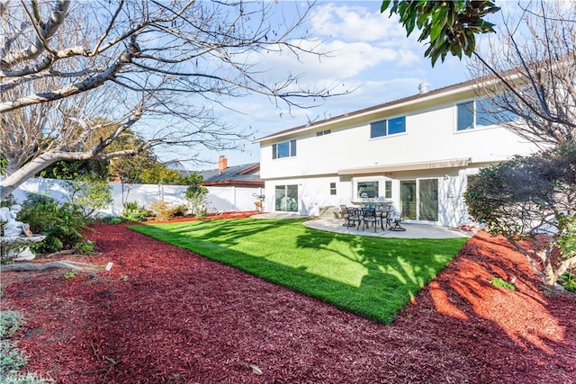 rear view of house with stucco siding, a fenced backyard, a lawn, and a patio