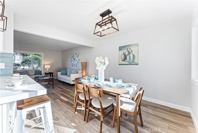 dining space with light wood-style floors, baseboards, and a notable chandelier