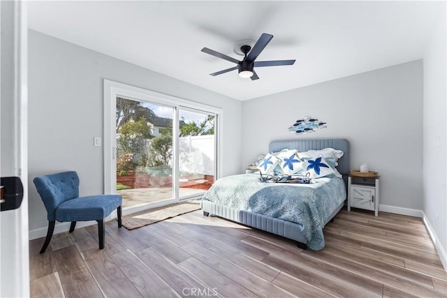 bedroom featuring access to outside, wood finished floors, a ceiling fan, and baseboards