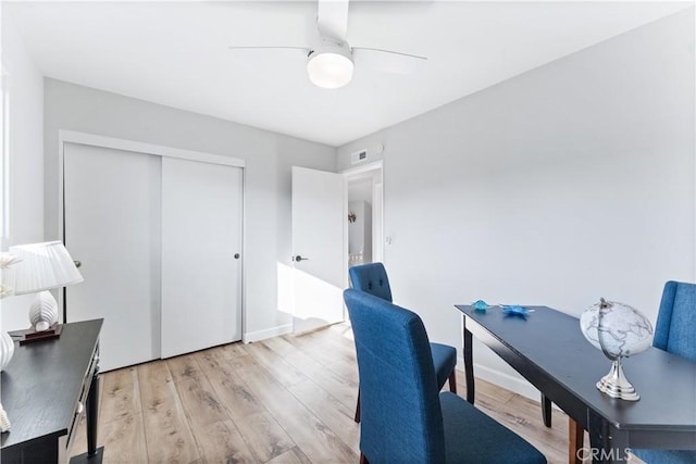 home office featuring visible vents, baseboards, light wood-style flooring, and a ceiling fan