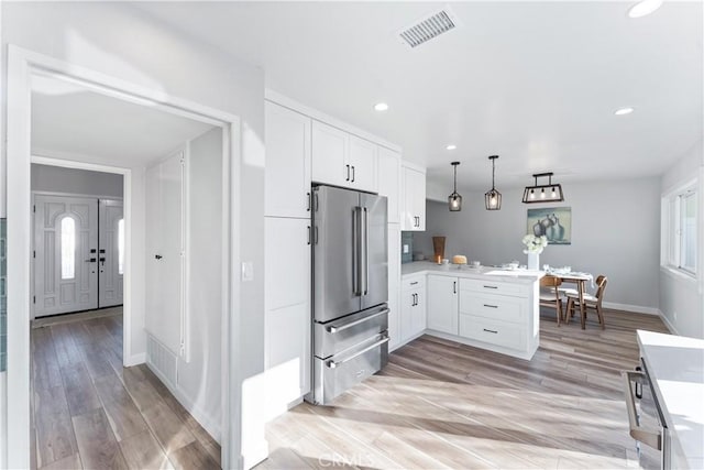 kitchen featuring light countertops, visible vents, white cabinets, a peninsula, and high end refrigerator