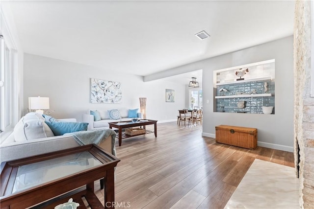 living room with baseboards, visible vents, and wood finished floors